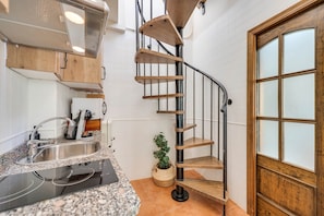 Eine Küche mit fest eingebautem Herd, einer Spüle und einer Wendeltreppe, die zu einer Holztür führt.