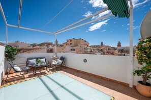 Eine Dachterrasse mit Pool, Sitzgelegenheiten und Blick auf die Stadt.