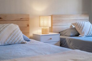 A bedroom with two beds, a bedside table with a lamp, and a wooden headboard. - Cozy and lovely apartment located in the historic center of Málaga. (Centro Histórico)