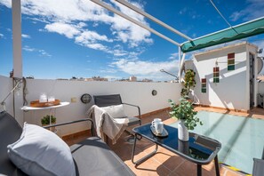 Terraza en la azotea con piscina, zona de estar y vistas al horizonte de la ciudad.