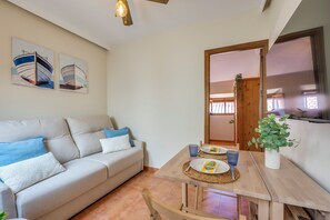 Ein Wohnzimmer mit einer Couch, einem Esstisch mit Tellern und Gläsern sowie einem Gemälde an der Wand.