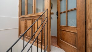 A wooden door with glass panels and a metal staircase leading to an interior space. - Cozy and lovely apartment located in the historic center of Málaga. (Centro Histórico)