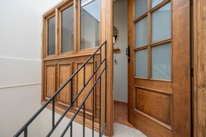 Eine Holztür mit Glassfeldern und eine Metalltreppe, die zu einem Innenraum führt.