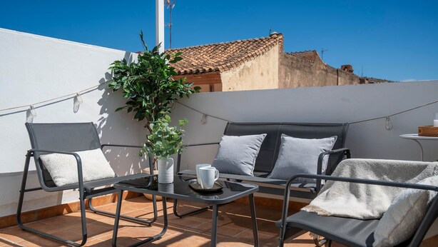 A rooftop terrace with a sofa, two chairs, a small table, and a potted plant. - Cozy and lovely apartment located in the historic center of Málaga. (Centro Histórico)