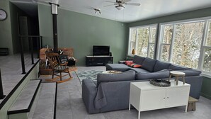 Uma sala de estar moderna com um sofá seccional, um armário branco, uma televisão e uma lareira.
