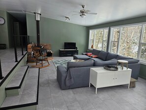 Ein modernes Wohnzimmer mit einem Ecksofa, einem weißen Schrank, einem Fernseher und einem Kamin.