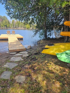 A wooden dock extending into a lake with two chairs and a hammock. - Family friendly lakeside cottage. (Kearney)