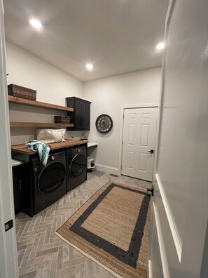 A laundry room with a washing machine, dryer, shelves, and a clock on the wall. - MIZ-ZOU football weekend home
Awesome  house on Hole #7 at Old Hawthorne (Columbia)