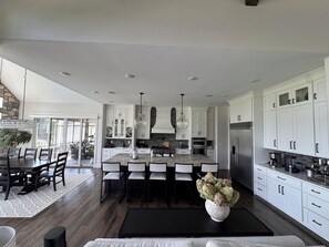 A modern kitchen with white cabinets, a central island, and a dining area with a table and chairs. - MIZ-ZOU football weekend home
Awesome  house on Hole #7 at Old Hawthorne (Columbia)