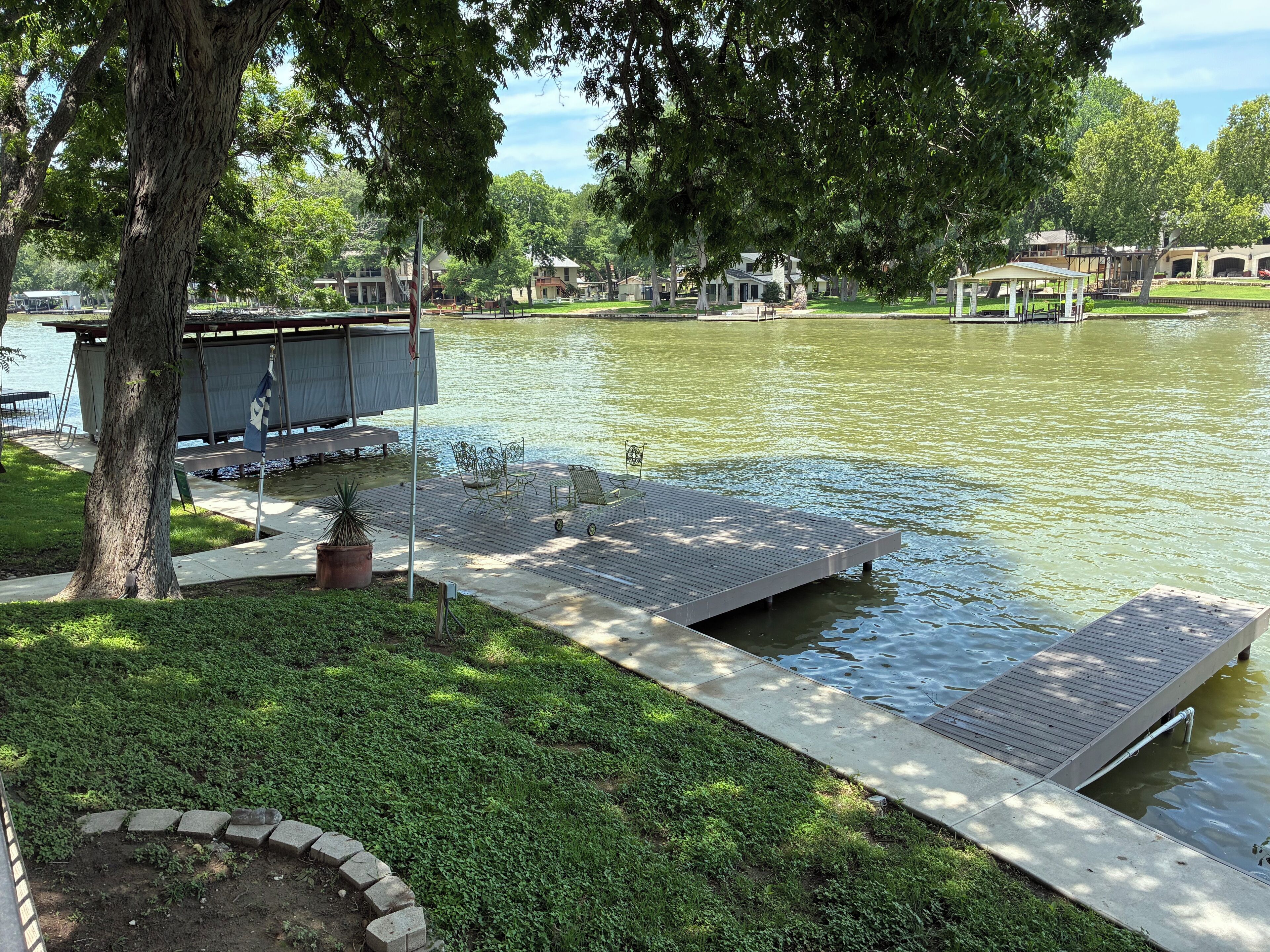 A lakeside park with a wooden dock, benches, and a gazebo.