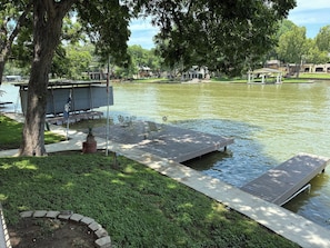 Un parque junto al lago con un muelle de madera, bancos y un pabellón.