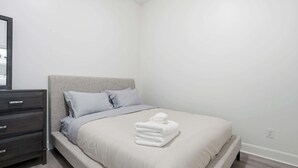 A bedroom with a bed, a dresser, and a mirror.