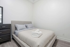A bedroom with a bed, a dresser, and a mirror.