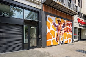 Ein Gebäude mit einer großen Giraffen-Mural-Bemalung an der Seite, einem geschlossenen Eingang mit Rollläden und einer Walgreens-Apotheke gegenüber.
