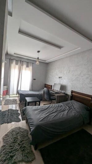 A bedroom with two beds, a desk, and a chair.