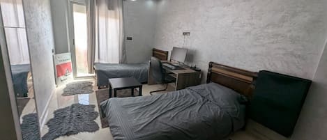 Une chambre avec deux lits, un bureau, une chaise et un ordinateur.
