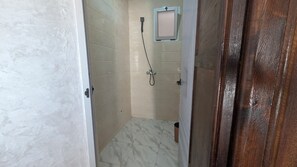 A bathroom with a shower, tiled walls, and a wooden door.