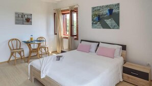 Quarto com cama, mesa de cabeceira e escrivaninha com cadeiras.