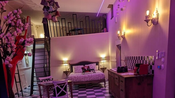 Een kamer met een geruite vloer, een bed met een bedsprei met patroon, een kleine tafel met stoelen, een kast en een whirlpool met digitaal display.