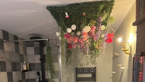 Een badkamer met een zwart-wit geruite vloer, een glazen douchecabine, een wandhaken voor handdoeken en een plank met toiletartikelen.