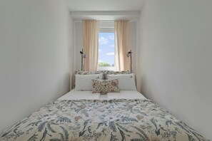 A narrow room with a bed, two lamps, and a window with curtains. - Boho Flow by Lion Apartments (Sopot)