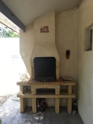A stone-built outdoor fireplace with a brick hearth, a small shelf, and a vent above it. - 3-bedroom vacation rental, 10 minutes from Jonzac, fully fenced (Rouffignac)