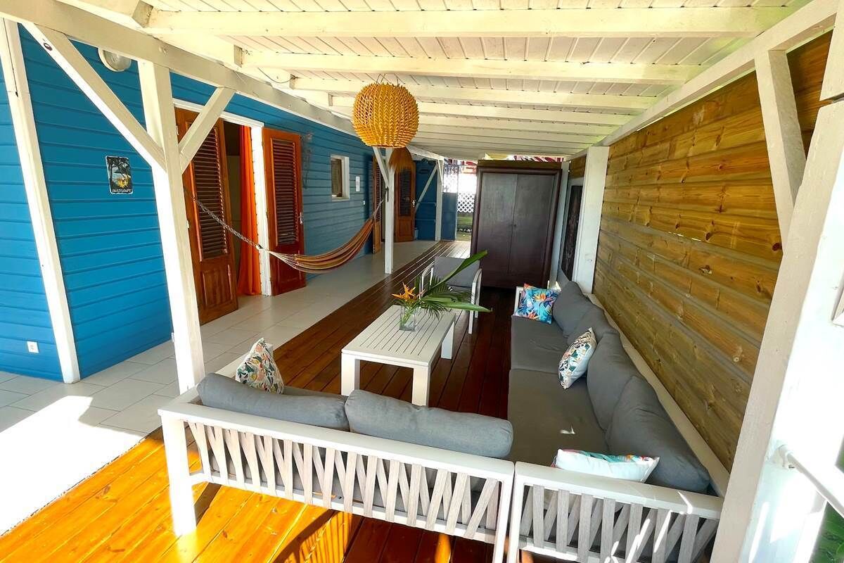 A covered outdoor seating area with a hammock, a table, and a sofa.
