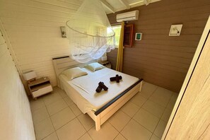 A bedroom with a bed, bedside tables, a mosquito net, and a window with curtains.