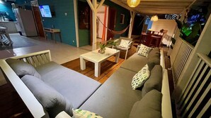 Ein gemütlicher Wohnbereich mit einer Couch, Sesseln, einem kleinen Tisch und einer Hängematte.