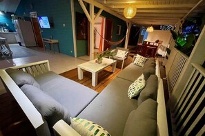 Ein gemütlicher Wohnbereich mit einer Couch, Sesseln, einem kleinen Tisch und einer Hängematte.