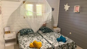 Ein Schlafzimmer mit zwei Betten, einem Moskitonetz und einer kleinen Schildkröten-Dekoration an der Wand.