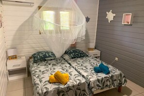 Ein Schlafzimmer mit zwei Betten, einem Moskitonetz und einer kleinen Schildkröten-Dekoration an der Wand.