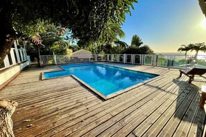 A wooden deck with a swimming pool, surrounded by a white fence and palm trees. - Villa Morphy, ocean view, pool, beach 3 minutes away, between DESHAIES and BOUILLANTE (Pointe-Noire)