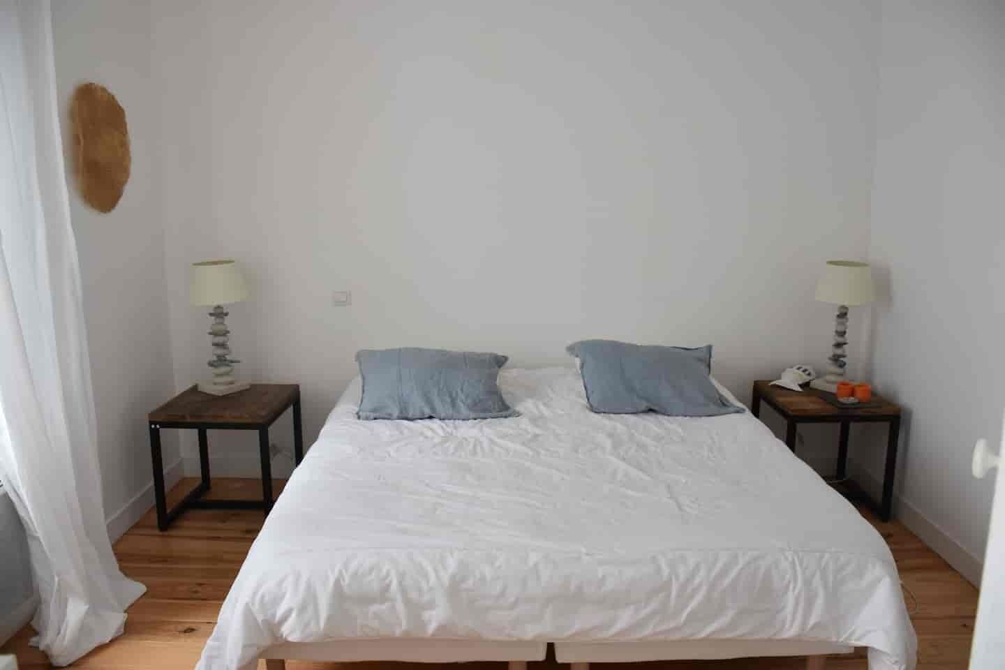 A bedroom with a single bed, two bedside tables, and two lamps.