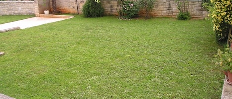 A well-maintained lawn with a stone wall and various plants.
