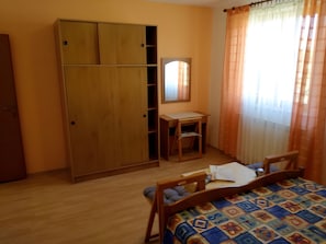 Ein Schlafzimmer mit einem Bett, einem Holzschrank, einem Schreibtisch und einem Spiegel.