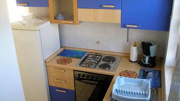 A compact kitchenette with a gas stove, a built-in oven, a sink, and a coffee maker.