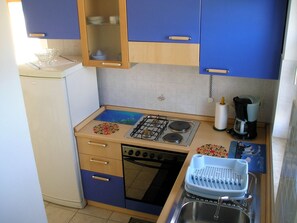 Une petite cuisine équipée avec une cuisinière à gaz, un four encastré, un évier et une machine à café.