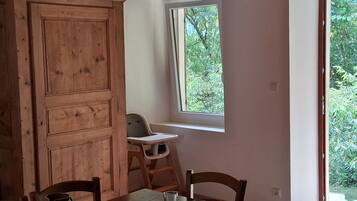 Un comedor con una mesa de madera, sillas, un jarrón y una ventana que da a zonas verdes.