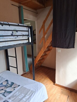 Ein Zimmer mit einem Stockbett, einer Holztreppe und einer Tür zu einem anderen Raum.