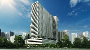 Ein Hochhaus mit mehreren Balkonen, umgeben von anderen Gebäuden und Grünflächen.