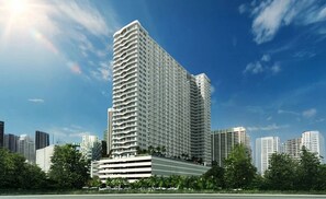 Ein Hochhaus mit mehreren Balkonen, umgeben von anderen Gebäuden und Grünflächen.
