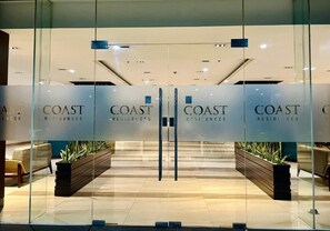 A modern interior with glass doors labeled 'COAST Residences.' - Fully furnished cozy 1-bedroom condo unit with AC for a staycation in Pasay City (Pasay City)
