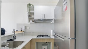 Una cuina moderna amb armaris blancs, un refrigerador d'acer inoxidable i una cuina de gas.
