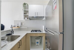 Eine moderne Küche mit weißen Schränken, einem Edelstahlkühlschrank und einem Gasherd.