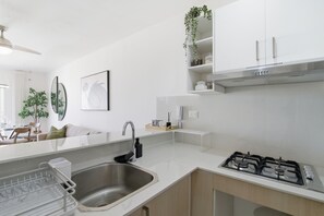 A modern kitchen with a stainless steel sink, a gas stove, and white cabinetry. - Cozy 1-bedroom Apt in Punta Cana with Private Terrace (Punta Cana)