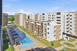 Un immeuble d’appartements moderne doté d’une piscine et d’un espace extérieur aménagé pour se détendre.