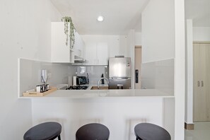 A modern kitchen with a central island, a built-in oven, and a refrigerator. - Cozy 1-bedroom Apt in Punta Cana with Private Terrace (Punta Cana)