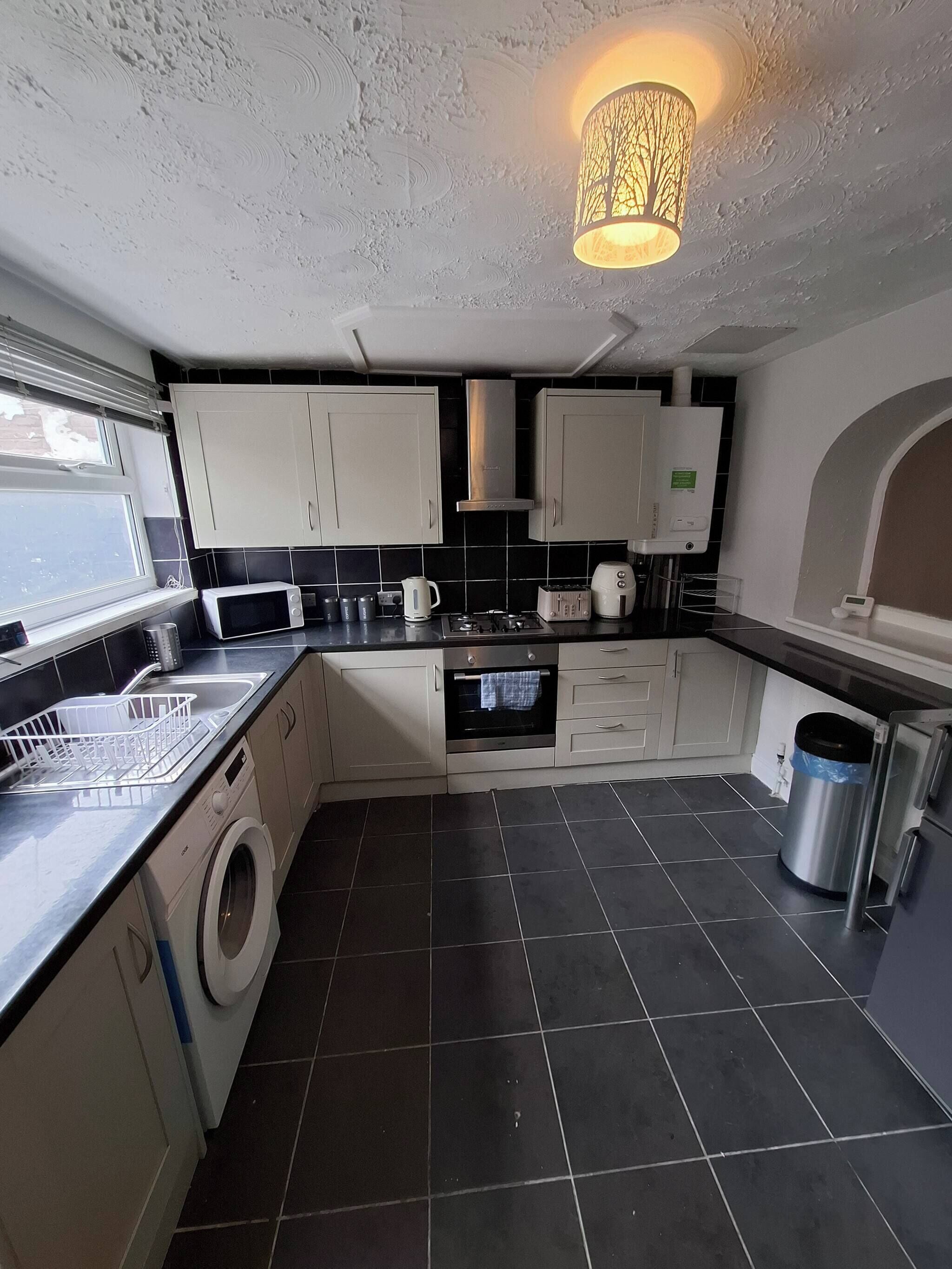 A compact kitchen with a washing machine, microwave, and oven.