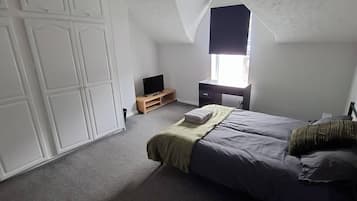 Quarto com cama, televisão, guarda-roupa e janela.